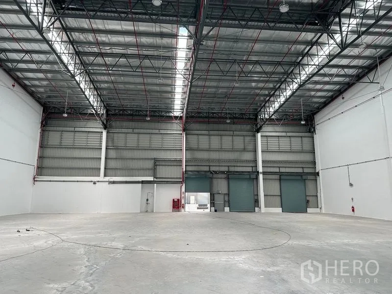 Warehouse for rent in Bang Phli, Samut Prakan - Warehouse interior with multiple roller shutter doors and visible fire safety piping.
