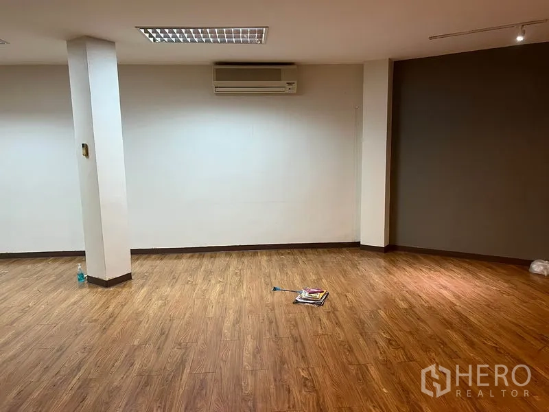 办公空间 出租在Khlong Toei, Bangkok - 宽敞工位角落，承重柱，木纹地板，灰色重点墙与分体空调。