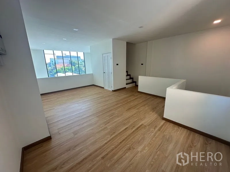 Home Office for rent in Wang Thonglang, Bangkok - Mezzanine workspace with stairs and a large window bringing in natural light.