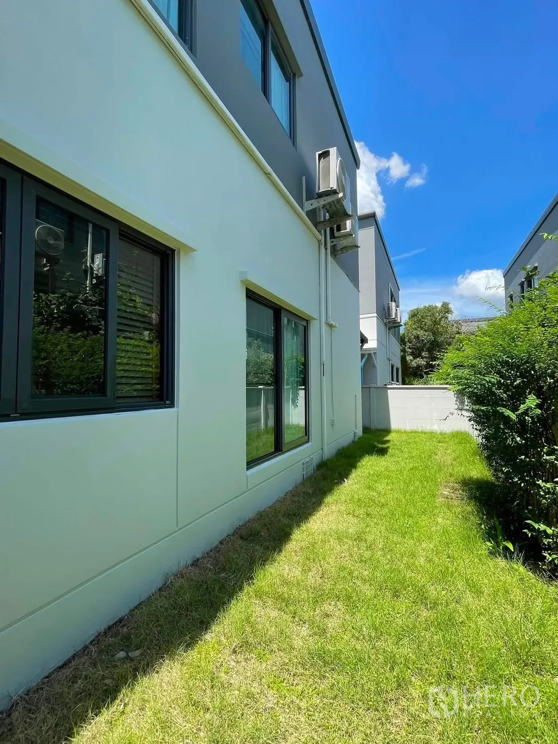 Detached House for rent in Bang Phli, Samut Prakan - Side yard with a green lawn along the exterior wall and windows of the house.
