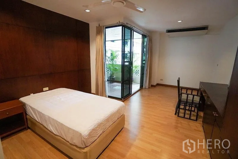 房间 出租在Watthana, Bangkok - 卧室铺木地板，带书桌与推拉门，连接葱郁阳台。