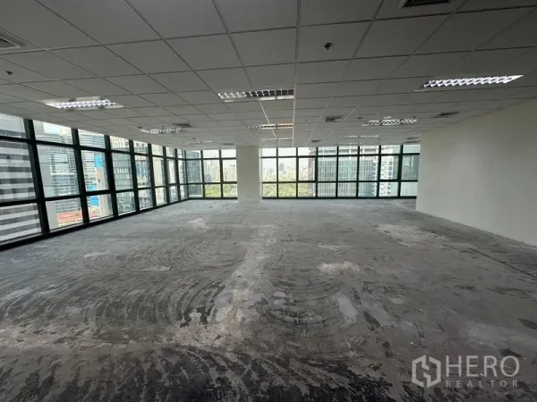 Office Space for rent in Bang Rak, Bangkok - Spacious unfurnished office floor with large windows and a central column overlooking the Bangkok skyline.