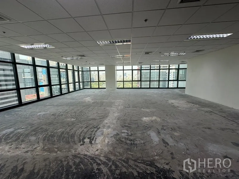 Office Space for rent in Bang Rak, Bangkok - Spacious unfurnished office floor with large windows and a central column overlooking the Bangkok skyline.