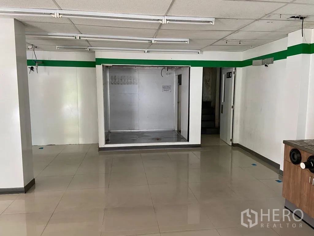 Retail Space for rent in Khlong Toei, Bangkok - Front wall showcasing a stainless-lined recess, doorway to stairs and tiled floor.