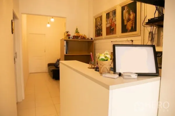 Shophouse for rent in Khlong Toei, Bangkok - Reception area with a white counter, shelving, and framed artwork.