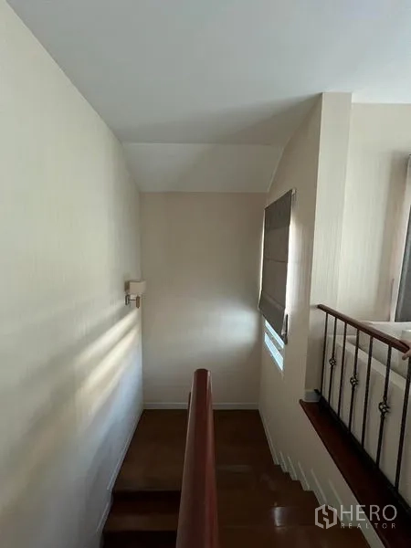 Detached House for rent or sale in Saphan Sung, Bangkok - Stairwell and landing with wooden handrail and small window.