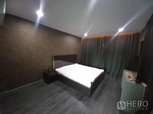 Townhouse for rent in Suan Luang, Bangkok - Minimalist bedroom with platform bed, accent lighting and full-length blackout curtains.