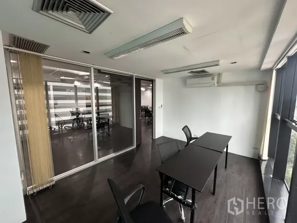 Office Space for rent in Watthana, Bangkok - Glass-walled meeting room with two desks, air conditioner and skyline views.