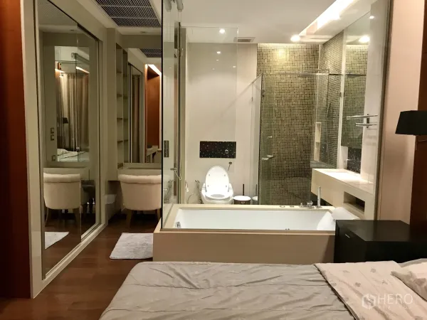 Condominium for rent or sale in Khlong Toei, Bangkok - Ensuite bathroom featuring a glass shower, mosaic wall tiles and a deep jacuzzi tub beside mirrored closets.