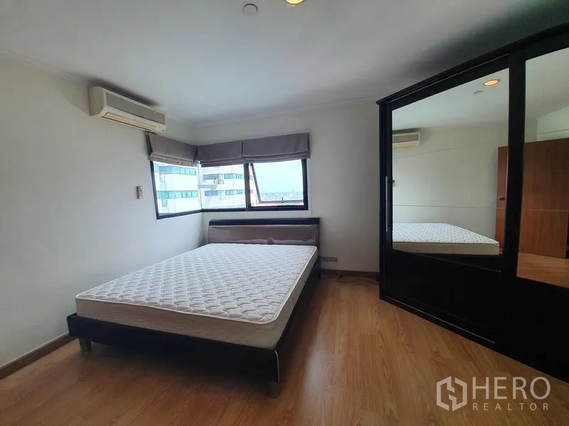Condominium for rent in Sathon, Bangkok - Second bedroom featuring panoramic corner windows and a large mirrored wardrobe.