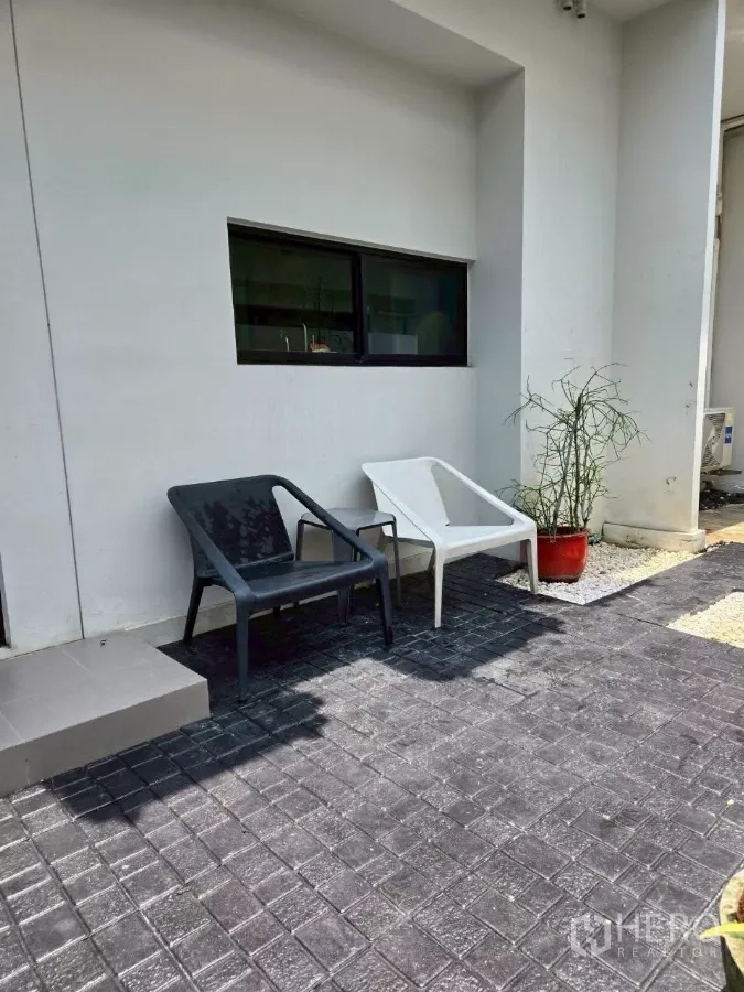 联排别墅 出租在Bang Phli, Samut Prakan - 室外小露台，两把椅子、盆栽与铺装地面，白色外墙。