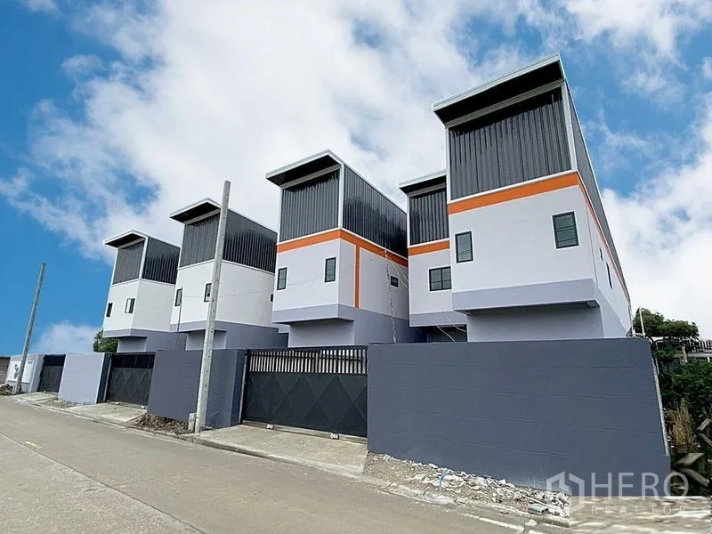 Factory for rent in Bang Bua Thong, Nonthaburi - Row of new gated factory units along a paved road with modern facades.