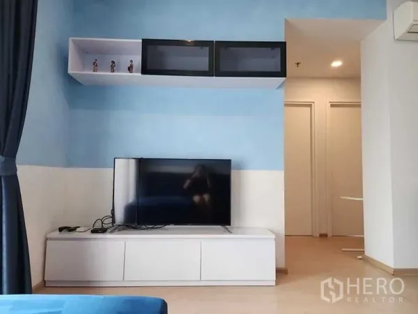 คอนโด ให้เช่า - ชั้นวางทีวีพร้อมชั้นลอยในห้องนั่งเล่นโทนสีฟ้าอ่อน
