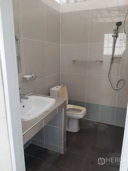 Factory for rent in Lam Luk Ka, Pathum Thani - Clean tiled bathroom with sink, toilet and handheld shower.