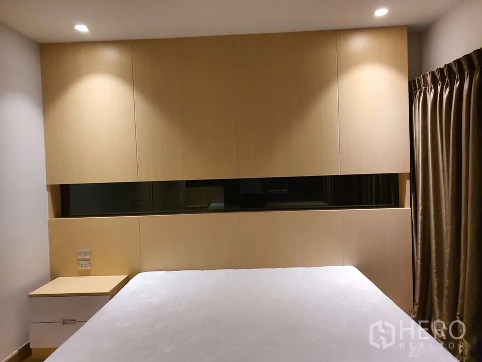Condominium for rent in Watthana, Bangkok - Second bedroom with minimalist headboard, bedside tables and blackout curtains.