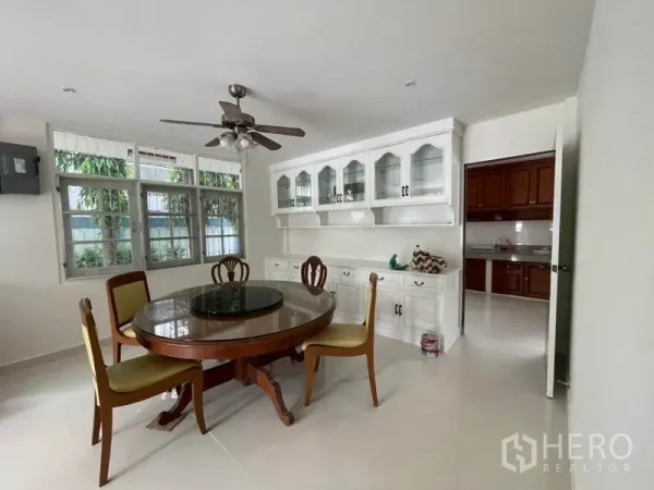 Detached House for rent in Khlong Toei, Bangkok - Dining room with round table, four chairs, ceiling fan and white display cabinet adjacent to the kitchen.