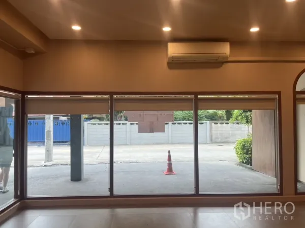 Retail Space for rent in Watthana, Bangkok - Ground-floor storefront with full-height display windows, ceiling spotlights, and a wall-mounted air conditioner.