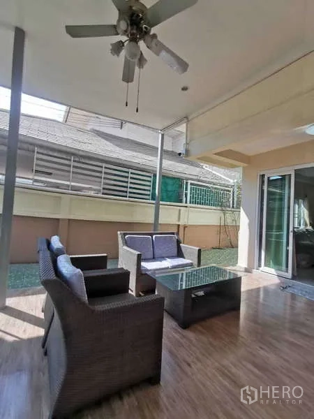 Townhouse for rent in Chatuchak, Bangkok - Covered terrace with rattan sofa set, ceiling fan and glass coffee table.