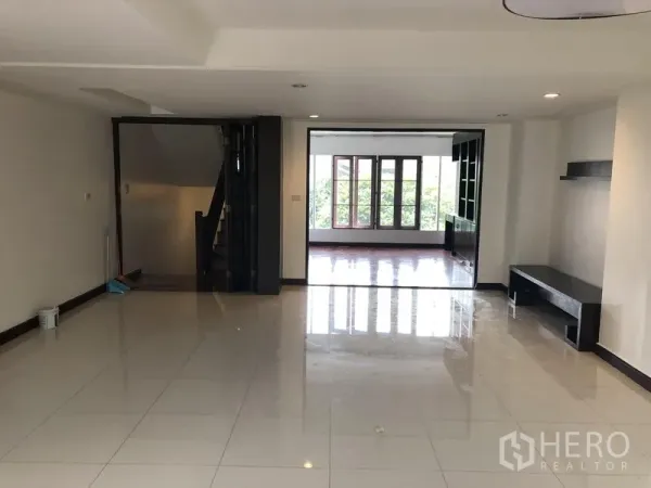 Townhouse for rent or sale in Watthana, Bangkok - Large family room with recessed lighting, staircase access and sliding doors to a sunroom.