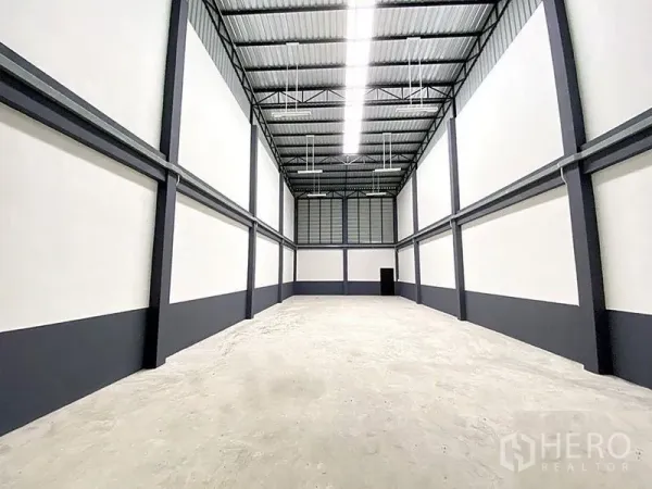 Factory for rent in Bang Bua Thong, Nonthaburi - High-ceiling warehouse hall with steel trusses, LED strip lighting and concrete floor.