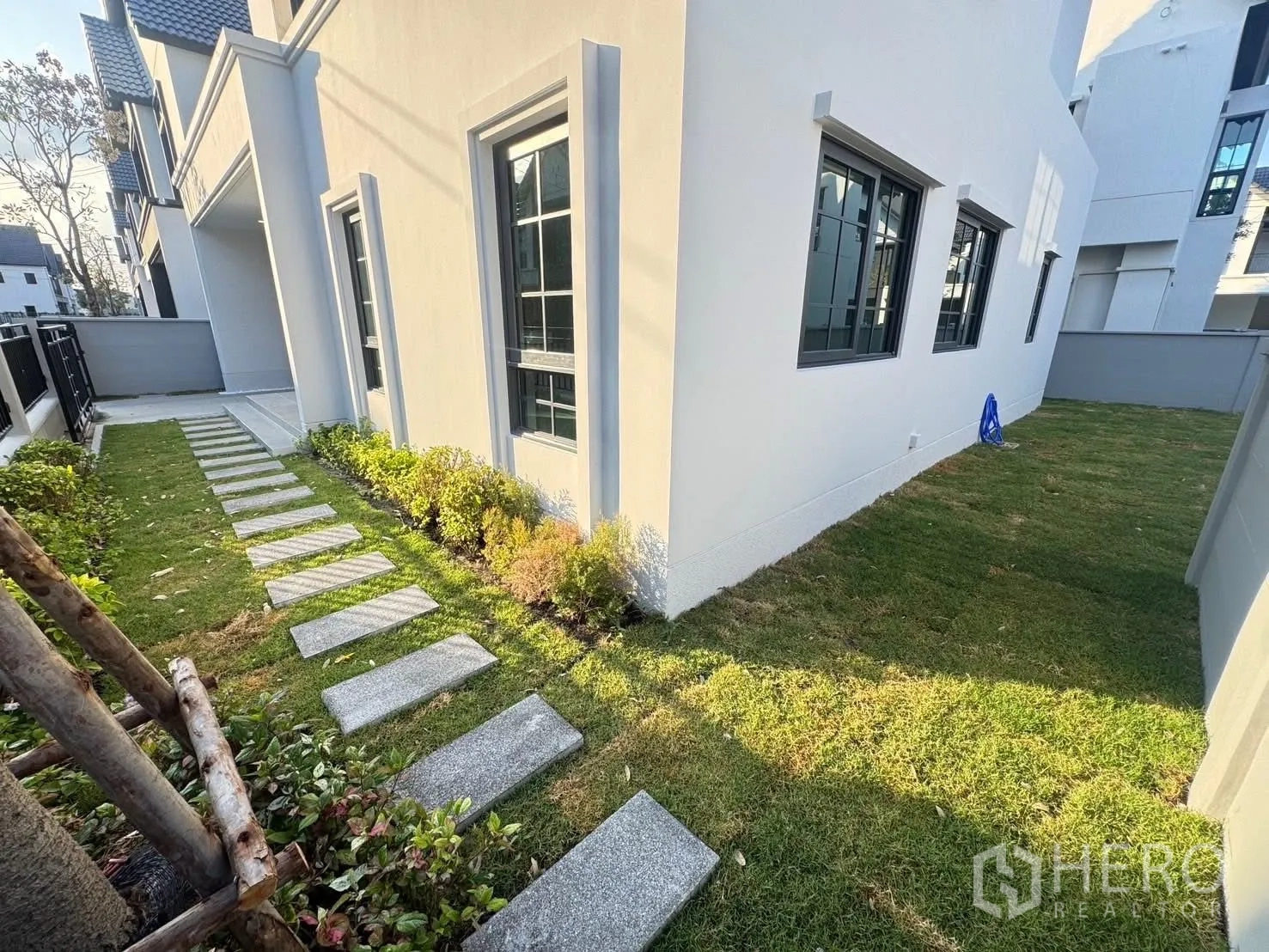 บ้าน for rent in Bang Phli, Samut Prakan - สวนข้างบ้านพร้อมทางเดินแผ่นหินขนานตัวบ้านสีขาวและแปลงพุ่มไม้