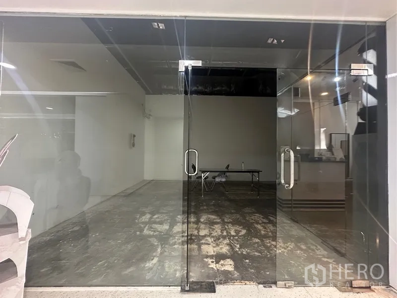 Retail Space for rent - Front view of the empty shop through clear glass doors within a commercial building.