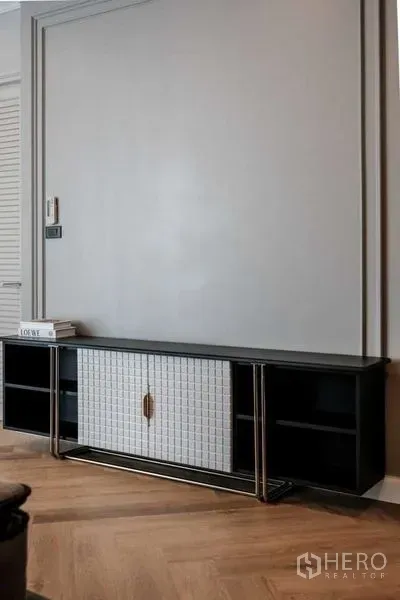 Condominium for rent in Khlong Luang, Pathum Thani - Built-in TV console with paneled feature wall and herringbone wood floor.