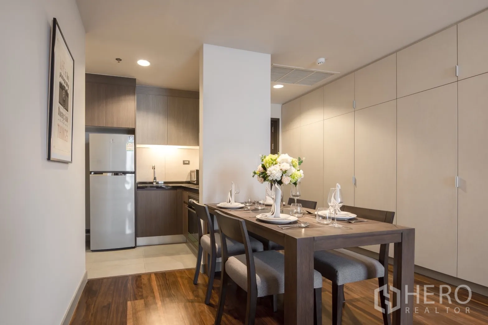 Condominium for rent in Khlong Toei, Bangkok - Dining area beside a compact kitchen with ample storage cabinets and soft lighting.