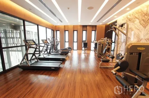 Condominium for rent in Watthana, Bangkok - Well-equipped fitness room with treadmills, weight machines and floor-to-ceiling windows.