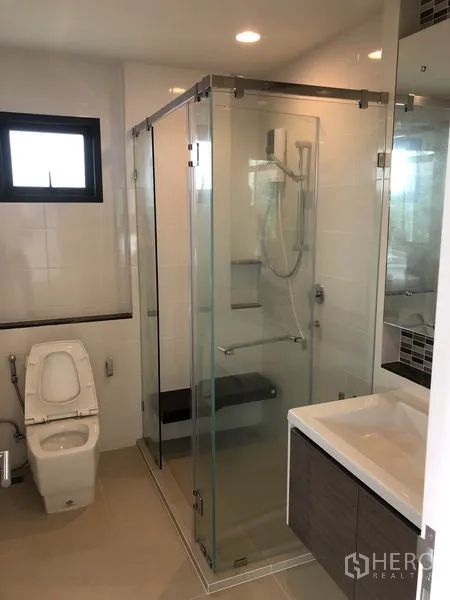Detached House for rent or sale in Bang Kapi, Bangkok - Modern bathroom with glass-enclosed shower, vanity and toilet.