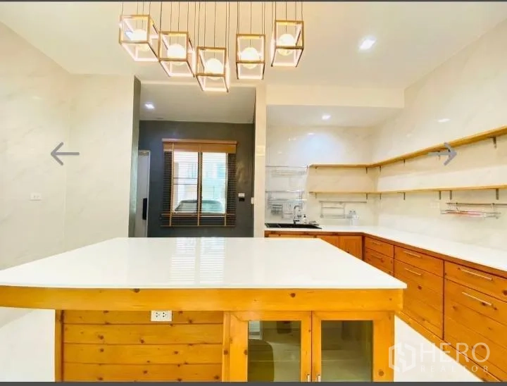 Detached House for sale in Saphan Sung, Bangkok - Spacious kitchen featuring a large white-top island and wood cabinets under modern lighting.
