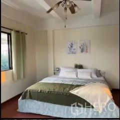 Detached House for rent in Phra Khanong, Bangkok - Sunlit bedroom with ceiling fan, large window and a neatly made bed.