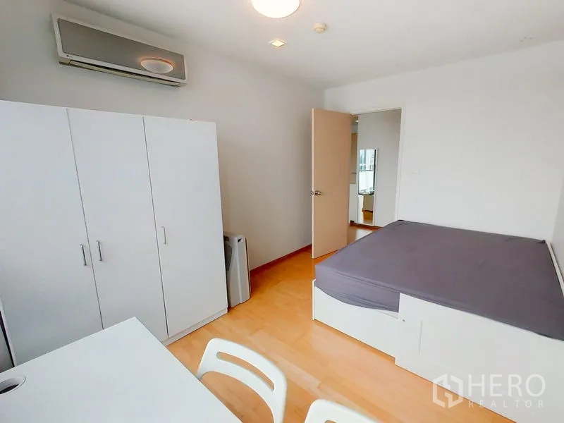 Condominium for rent in Khlong Toei, Bangkok - Minimal bedroom featuring platform bed, wardrobe and desk with air conditioning.