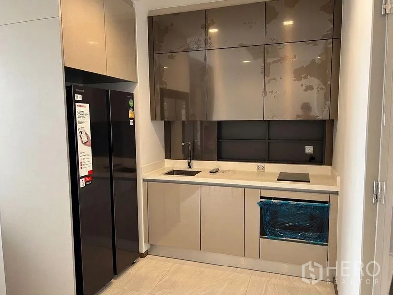 Condominium for rent in Ratchathewi, Bangkok - Modern built-in kitchen with glossy cabinets, sink, hob and double-door fridge in The Address Siam condo.