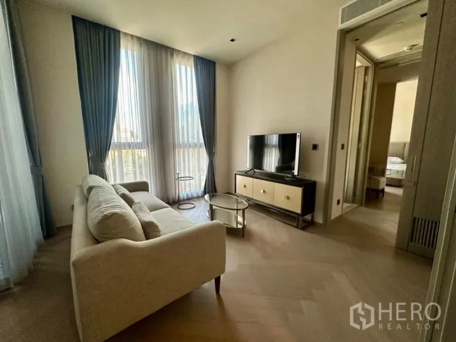 Condominium for rent - Cozy lounge with sofa, glass coffee table and sheer curtains.