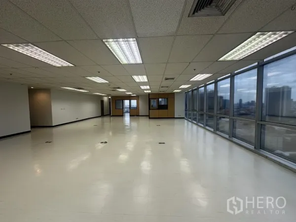 Office Space for rent - Long open workspace with suspended ceiling, air vents, floor boxes, and a window wall.