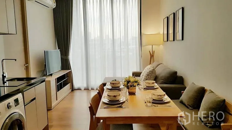 Condominium for rent in Khlong Toei, Bangkok - Open kitchen–dining area set for meals, adjoining lounge and floor-to-ceiling window.