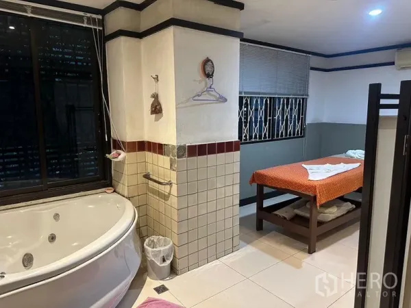 Shophouse for rent in Phra Khanong, Bangkok - Spa room featuring a corner jacuzzi bathtub, tiled walls and a massage bed by the window.