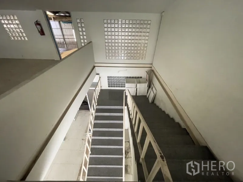 Warehouse for rent in Prawet, Bangkok - Interior staircase with glass-block wall leading to mezzanine offices.