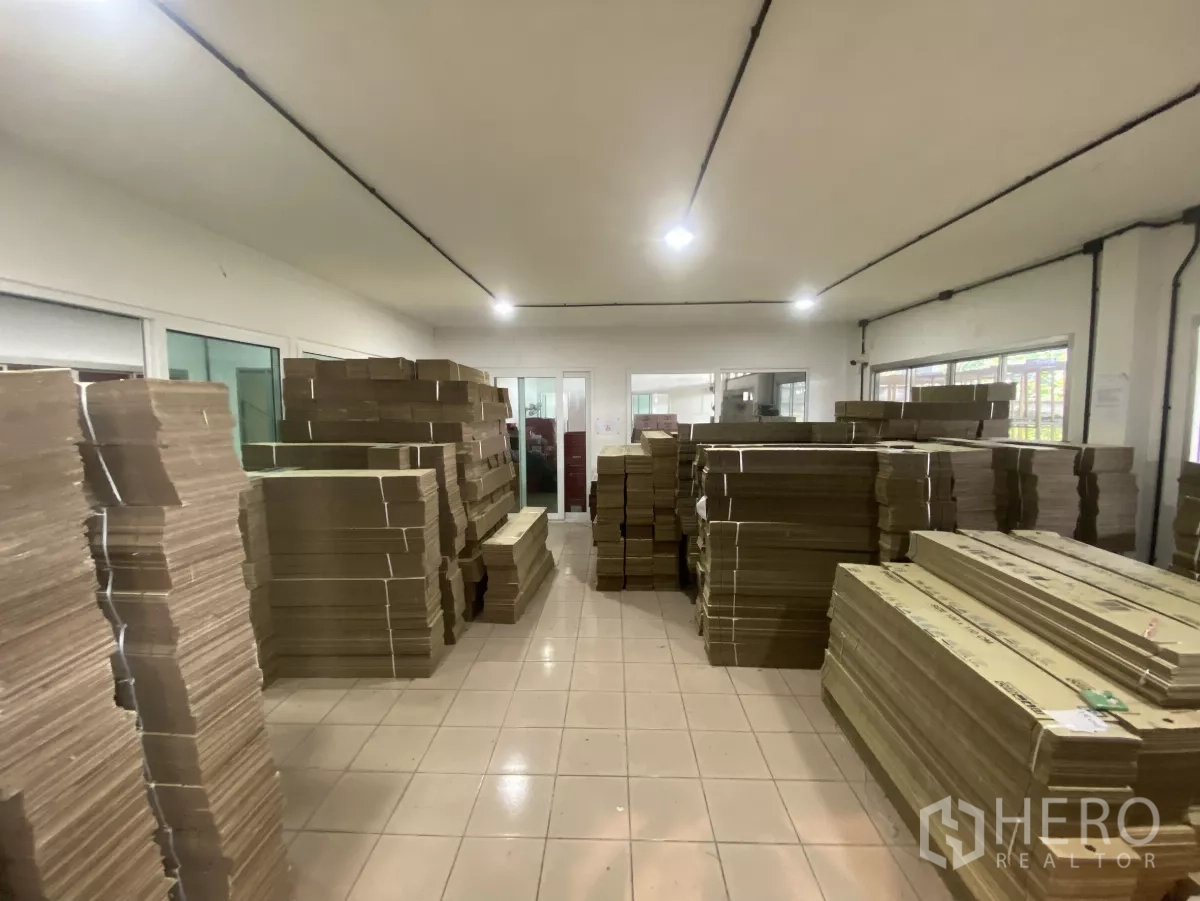 工厂 出租在Mueang Nakhon Pathom, Nakhon Pathom - 明亮的存储室，瓷砖地面，堆放大量扁平纸板。