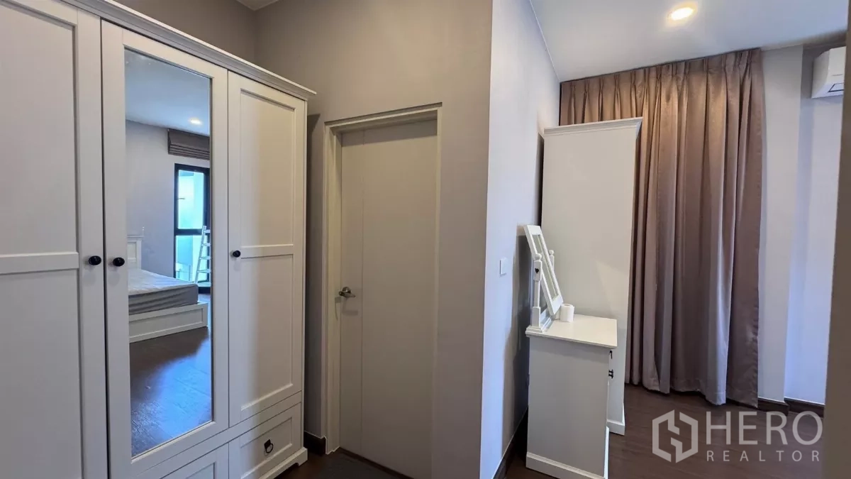 Detached House for rent or sale in Saphan Sung, Bangkok - View of dressing area with white wardrobes and door to an ensuite, neutral color palette.