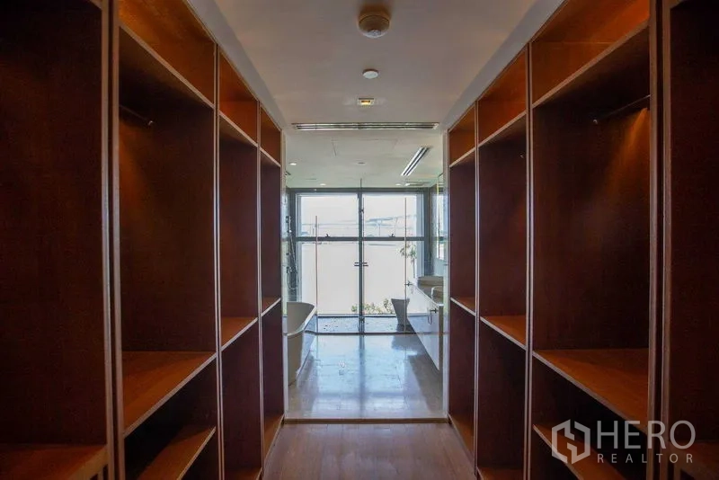公寓 出租在Yan Nawa, Bangkok - 步入式衣帽间走廊，内置木质柜体，尽头通向带浴缸的明亮卫浴