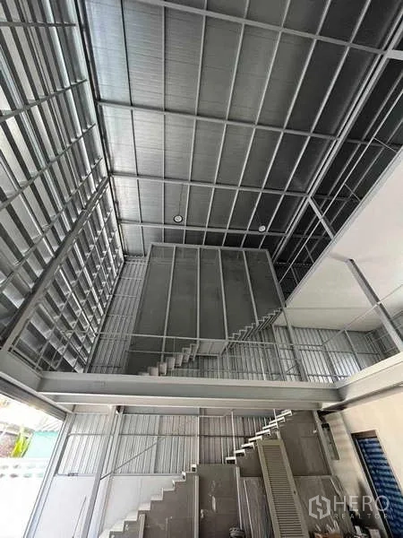 Home Office for rent or sale - High-ceiling industrial hall with metal cladding, mezzanine levels and stairs.