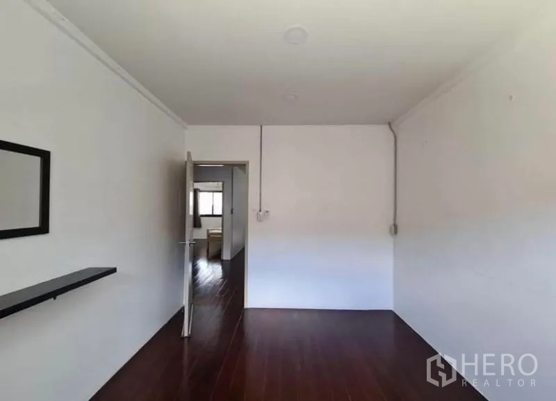 Townhouse for rent in Chatuchak, Bangkok - Upper floor landing with glossy wood floors and doors to bedrooms and bathrooms.