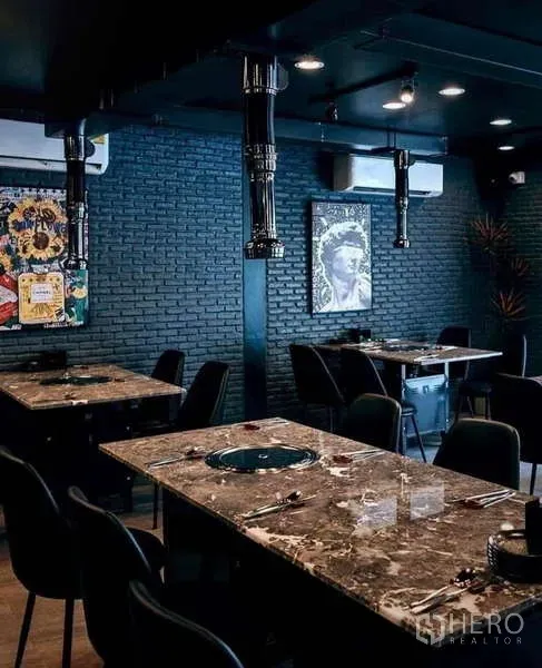 Detached House for rent in Watthana, Bangkok - Spacious dining room with multiple stone-top tables, black chairs and exposed ventilation pipes.