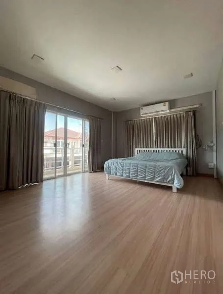 Detached House for rent in Bang Phli, Samut Prakan - Spacious master bedroom with wood flooring, air conditioning and sliding balcony doors.