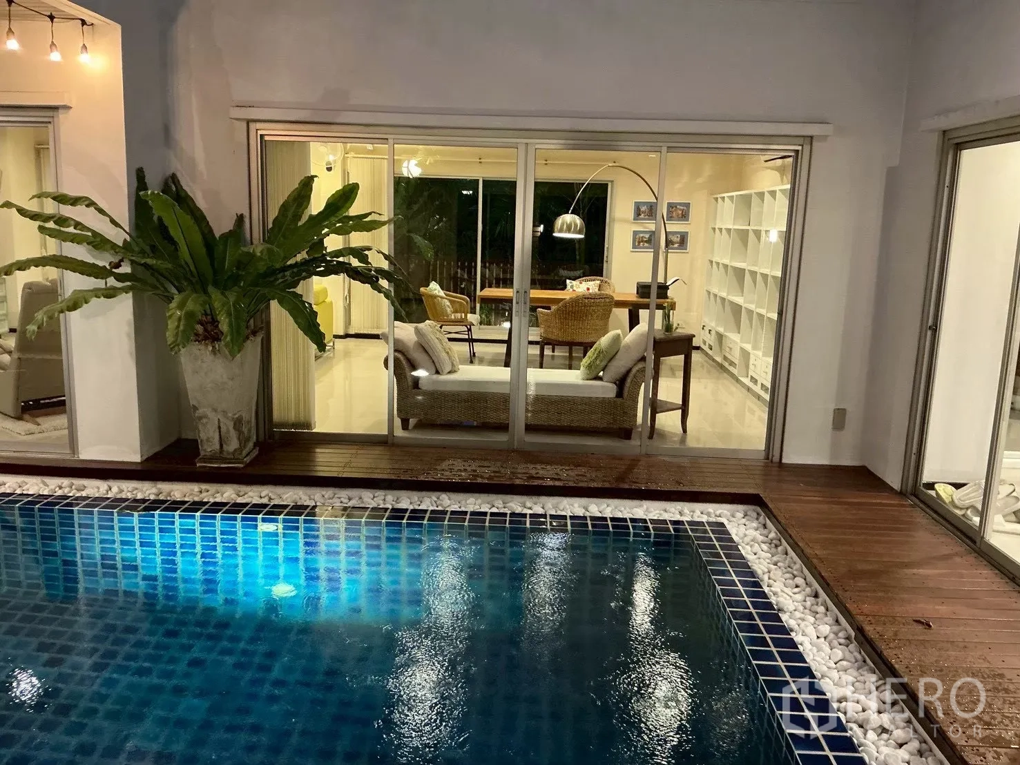 独栋房屋 for sale in Suan Luang, Bangkok - 泳池畔望向客厅，宽大的玻璃推拉门相连。