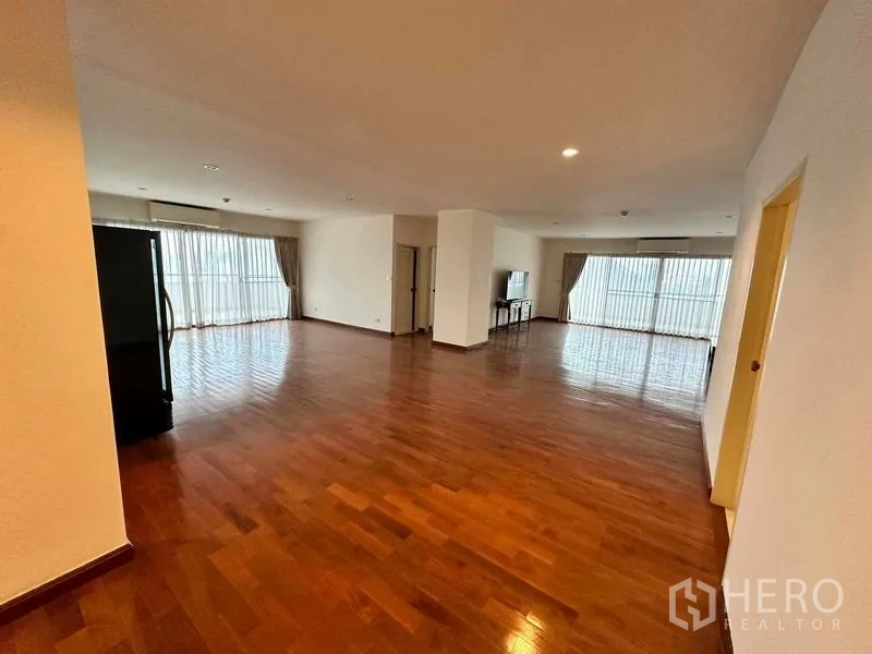 Condominium for rent in Bangkok - Open-plan living and dining space with multiple curtain-lined windows and a double-door refrigerator.