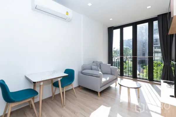 Condominium for rent in Watthana, Bangkok - Compact dining nook with marble-top table and two teal chairs beside a sunlit window.