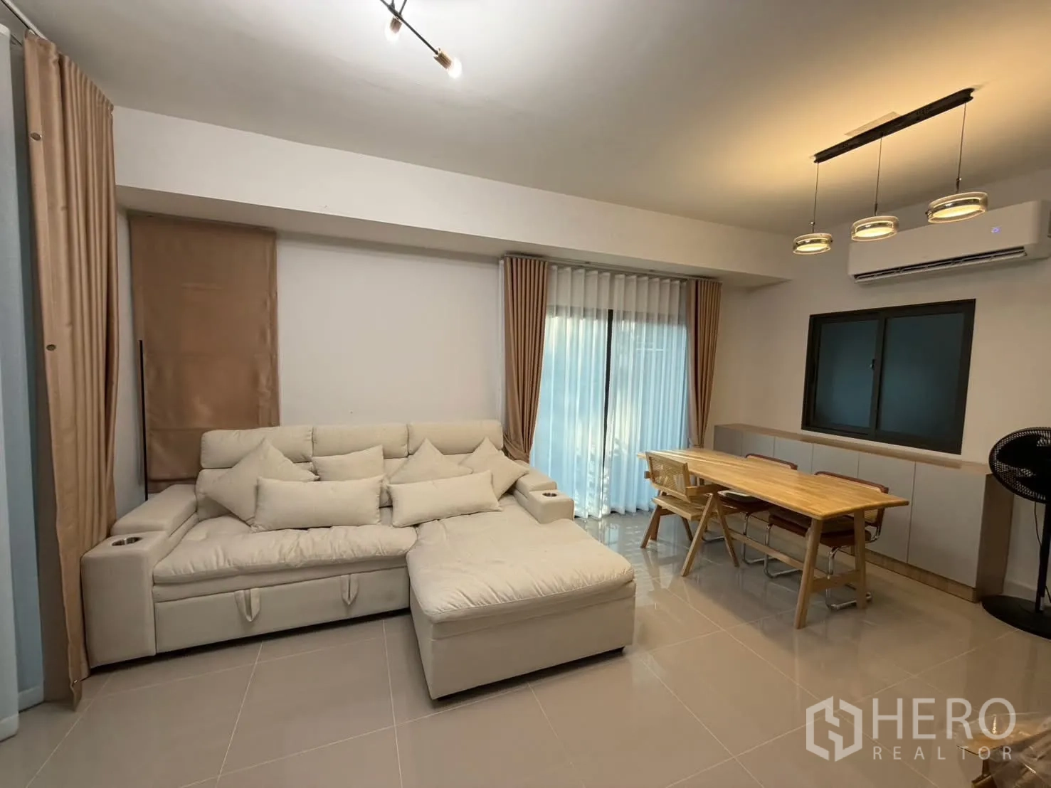 联排别墅 for rent in Bang Phli, Samut Prakan - 客餐厅一体，米色转角沙发、木质餐桌、吊灯与空调。
